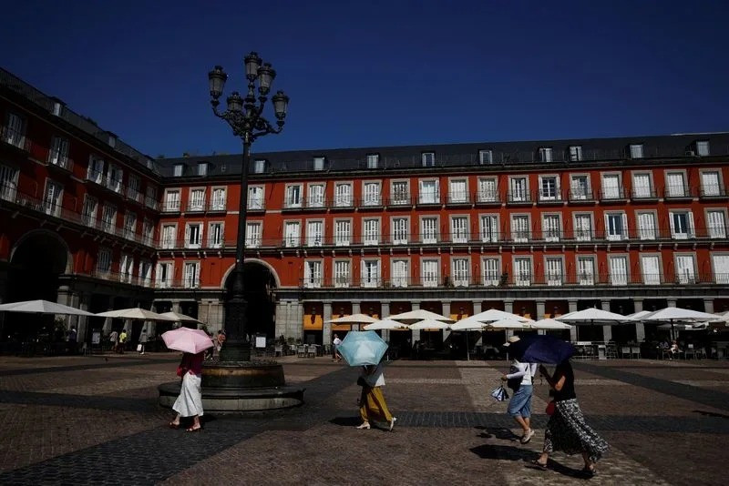 Du khách che dù trong lúc tham quan Quảng trường Plaza Mayor trong đợt sóng nhiệt ở Madrid, Tây Ban Nha, ngyaf 4-8-2025. Ảnh: Reuters 8a0a9202ad13ec273fd0388ba3225a9c.jpg