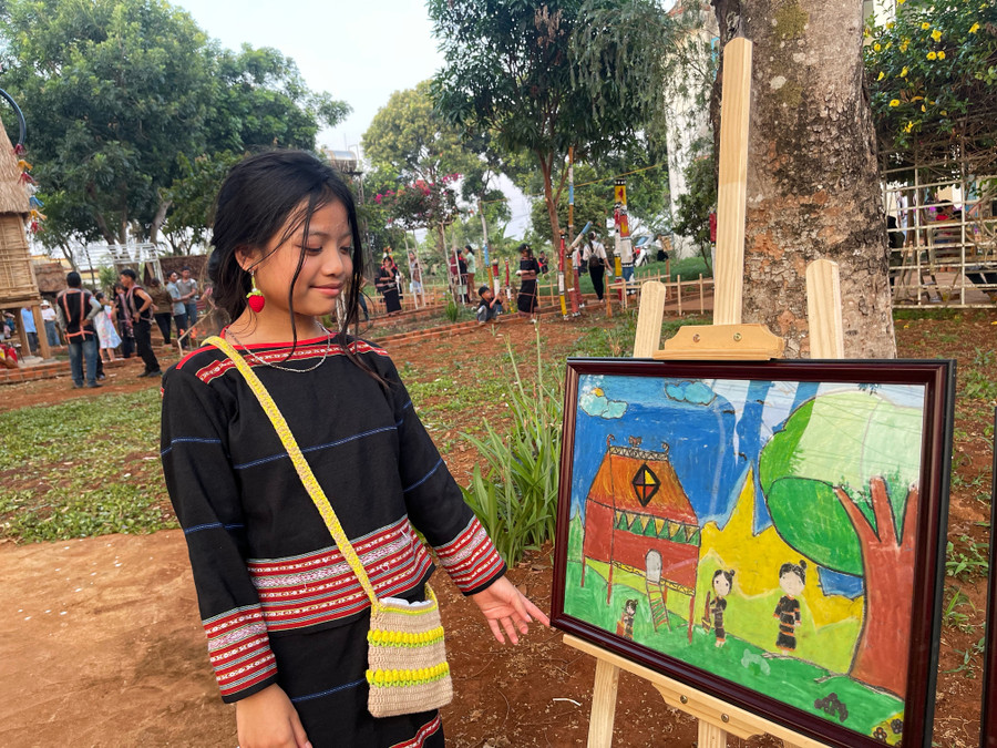Em Ksor Thư-học sinh lớp 6 đeo hoa tai và túi của câu lạc bộ đan móc len. Trong ảnh: em giới thiệu bức tranh vẽ làng của mình ở xã Ia O, huyênk Ia Grai. Ảnh: Hoàng Ngọc