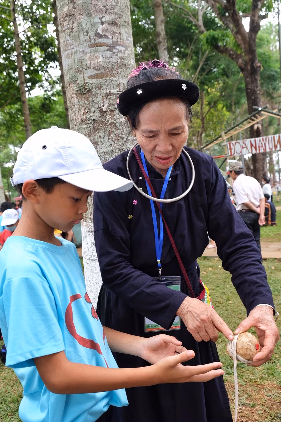 Bà Nguyễn Thị Đền (dân tộc Tày)-xã Kon Thụp, huyện Mang Yang hướng dẫn học sinh trường Tiểu học Kim Đồng (huyện Ia Grai) cách chơi trò chọi cù. Ảnh: Hoàng Ngọc