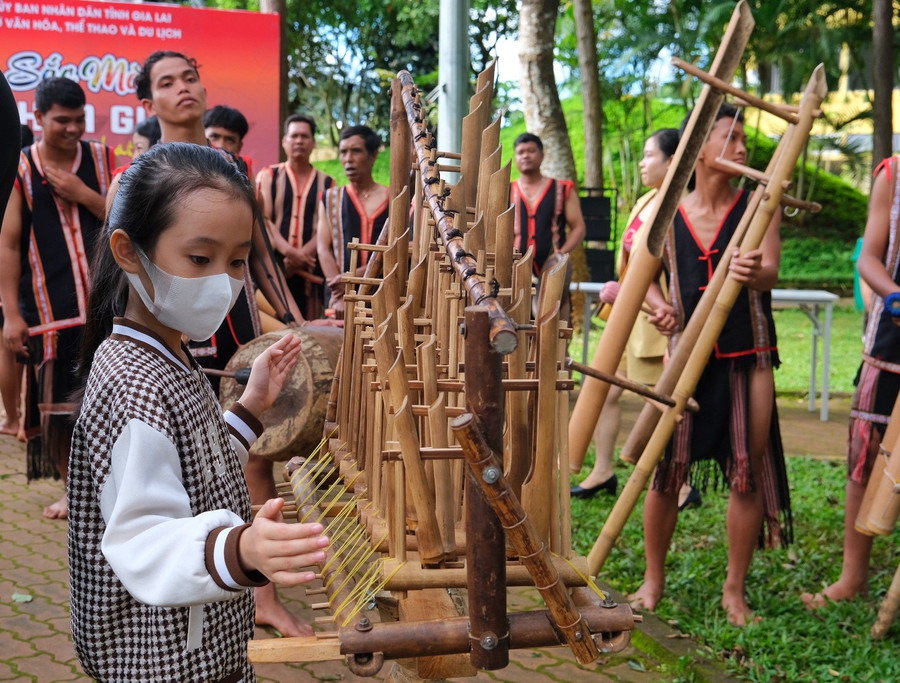 Một em bé chơi thử cây đàn klek klok-nhạc cụ từ tre nứa vô cùng độc đáo. Ảnh: Hoàng Ngọc