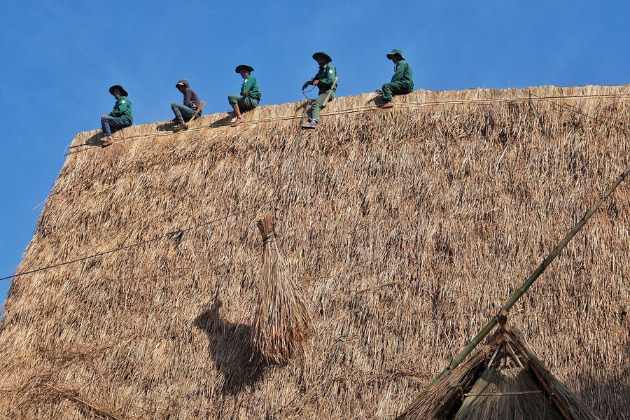Từng bó tranh được đưa lên đỉnh mái bằng ròng rọc dây thừng Từng bó tranh được đưa lên đỉnh mái bằng ròng rọc dây thừng