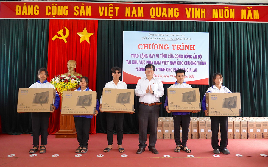 Phó Giám đốc Sở GD-ĐT Trần Bá Công trao tặng máy vi tính cho các em học sinh. Ảnh: Mộc Trà