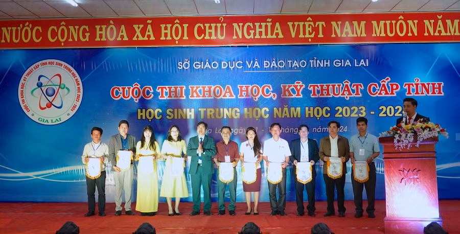 Phó Giám đốc Sở GD-ĐT Trần Bá Công (thứ 5 từ trái sang) trao cờ lưu niệm cho các đơn vị có dự án tham gia cuộc thi. Ảnh: Mộc Trà
