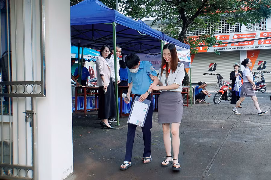 Một thí sinh bị đau chân được hỗ trợ vào phòng thi tại điểm thi Trường THPT chuyên Hùng Vương (TP. Pleiku). Ảnh: Đ.T