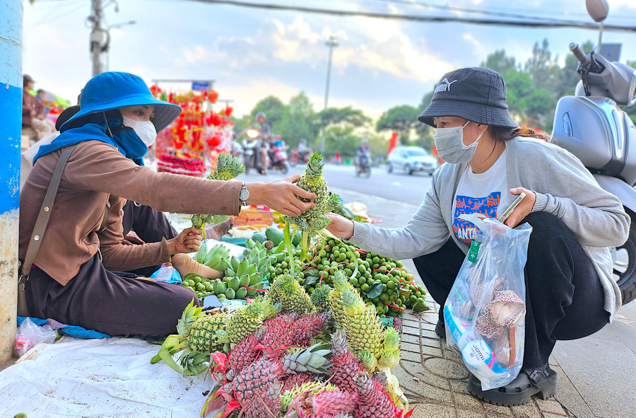 Chị Nay Loan (bìa trái; làng Ô Rê 1, xã Ia Grăng, huyện Ia Grai) đã có mặt tại khu vực ngã ba Hoa Lư (TP. Pleiku) từ sáng 27 tháng Chạp để bày bán “lộc xuân”. Ảnh: Mộc Trà