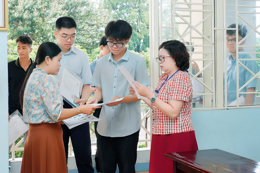 Cán bộ coi thi kiểm tra thông tin của thí sinh trước khi vào phòng thi. Ảnh: Đ.T Cán bộ coi thi kiểm tra thông tin của thí sinh trước khi vào phòng thi. Ảnh: Đ.T