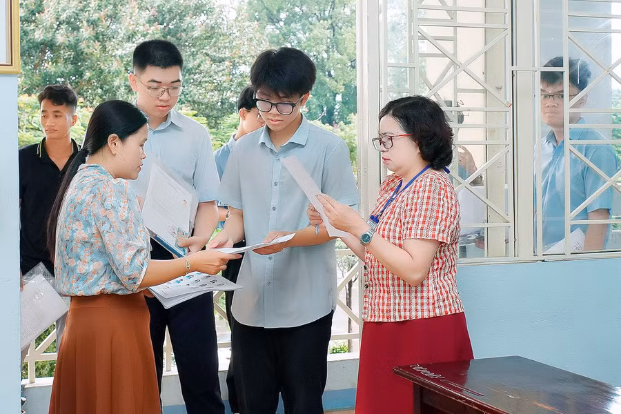 Cán bộ coi thi kiểm tra thông tin của thí sinh trước khi vào phòng thi. Ảnh: Đ.T