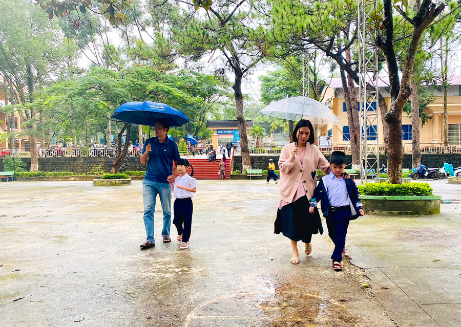 Sáng 22-8, trên địa bàn TP. Pleiku có mưa nhẹ. Nhiều phụ huynh đã đội mưa đưa con đến tựu trường đúng giờ. Ảnh: Mộc Trà