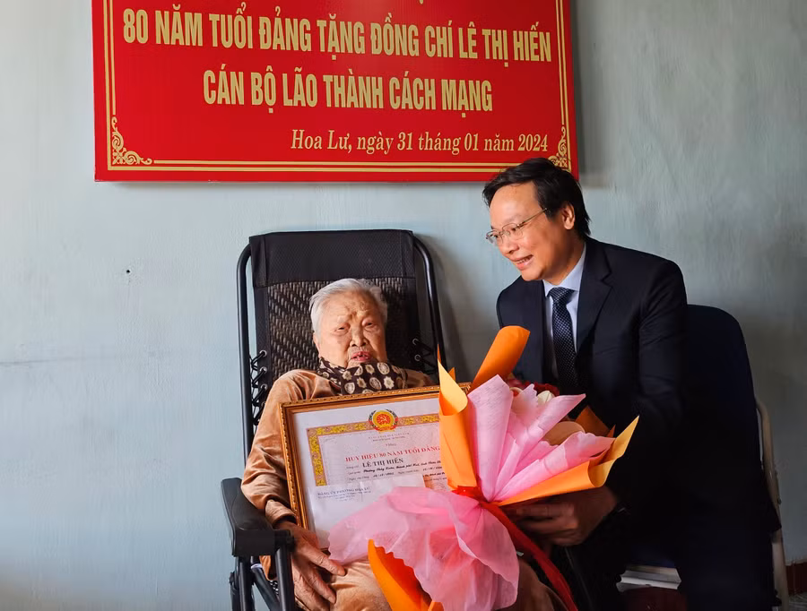 Phó Bí thư Tỉnh ủy, Chủ tịch UBND tỉnh Trương Hải Long trao huy hiệu 80 năm tuổi Đảng và tặng hoa chúc mừng đảng viên Lê Thị Hiến. Ảnh: Mộc Trà