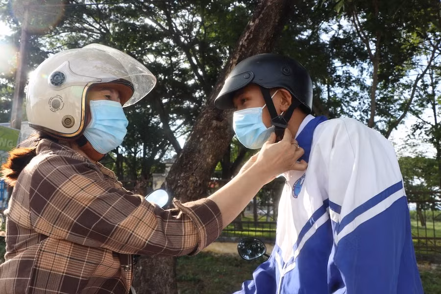 Phụ huynh ân cần đội mũ bảo hiểm cho con sau khi kết thúc ngày thi đầu tiên. Ảnh: Ngọc Minh