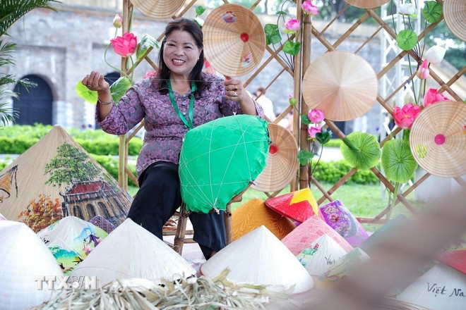 សិប្បករ Ta Thu Huong ផលិតមួករាងសាជីដោយផ្ទាល់នៅមហោស្រពទេសចរណ៍ហាណូយឆ្នាំ 2025។ (រូបថត៖ Khanh Hoa/VNA) Nghệ nhân Tạ Thu Hương trực tiếp làm nón lá tại Lễ hội Du lịch Hà Nội 2025. (Ảnh: Khánh Hòa/TTXVN)