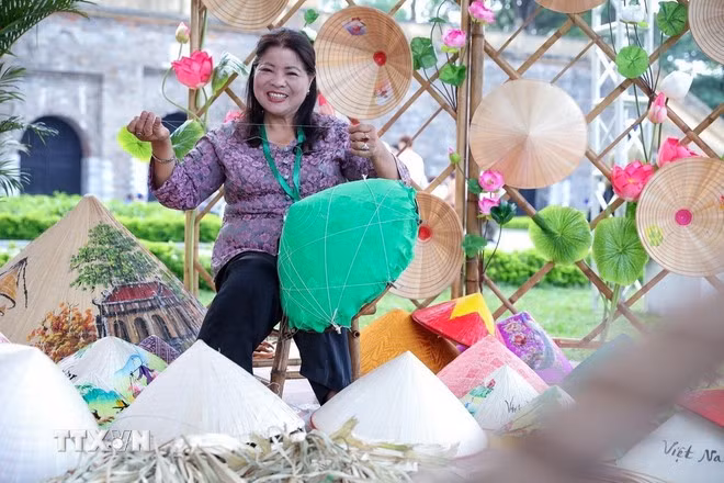Nghệ nhân Tạ Thu Hương trực tiếp làm nón lá tại Lễ hội Du lịch Hà Nội 2025. (Ảnh: Khánh Hòa/TTXVN)