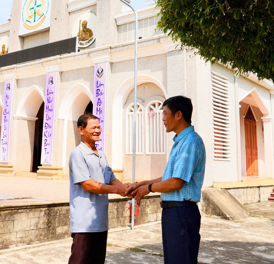 Ông Nguyễn Văn Minh (bìa trái, Trưởng Ban Công tác Mặt trận thôn Xuân Phương, Tổ trưởng Tổ bầu cử số 10) gặp gỡ linh mục Trần Văn Đức, Chánh xứ Giáo xứ Gò Dài để phối hợp tuyên truyền bầu cử.. Ảnh: Nguyễn Muội