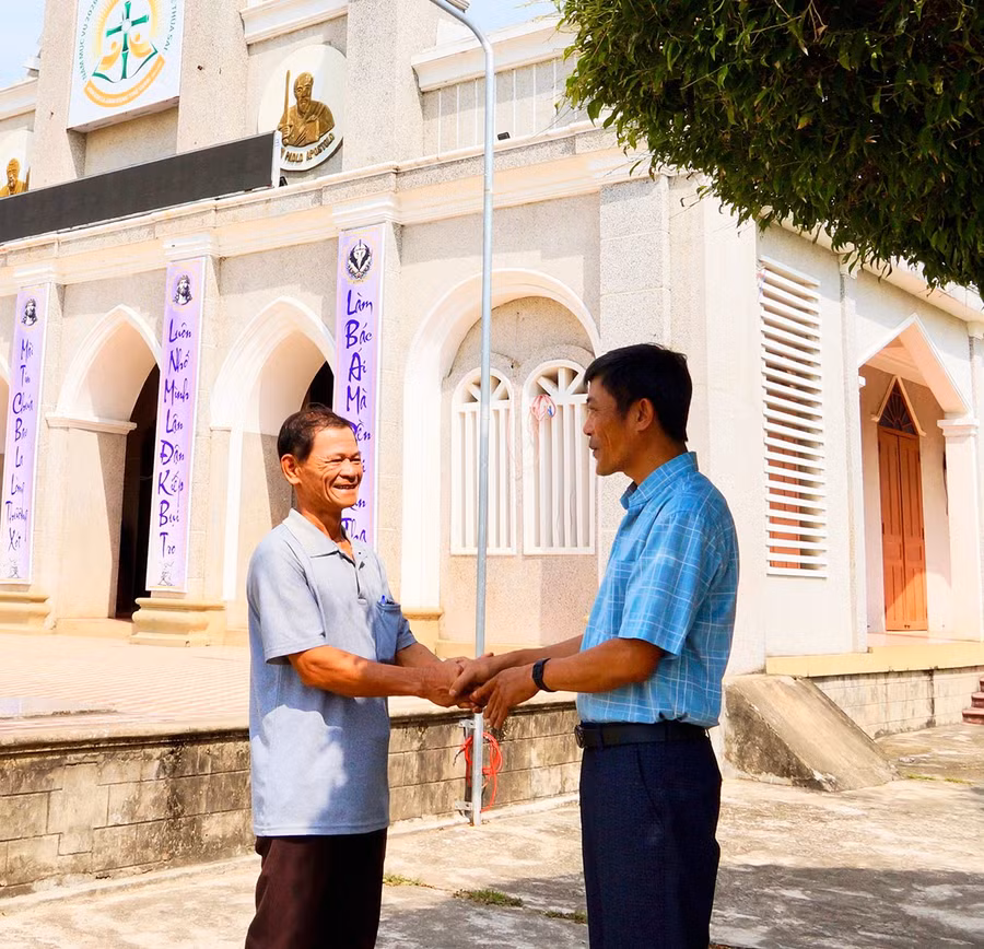 Ông Nguyễn Văn Minh (bìa trái, Trưởng Ban Công tác Mặt trận thôn Xuân Phương, Tổ trưởng Tổ bầu cử số 10) gặp gỡ linh mục Trần Văn Đức, Chánh xứ Giáo xứ Gò Dài để phối hợp tuyên truyền bầu cử.. Ảnh: Nguyễn Muội