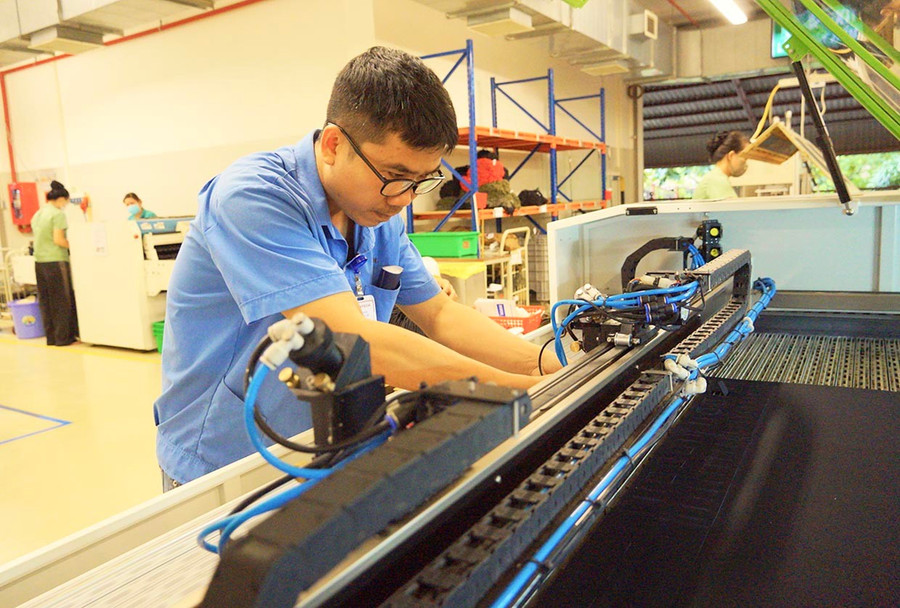 Anh Võ Sỹ Hậu điều chỉnh máy cắt laser cho phù hợp với nhiệm vụ của người lao động tại xưởng sản xuất. Ảnh: Nguyễn Muội 7-1.jpg