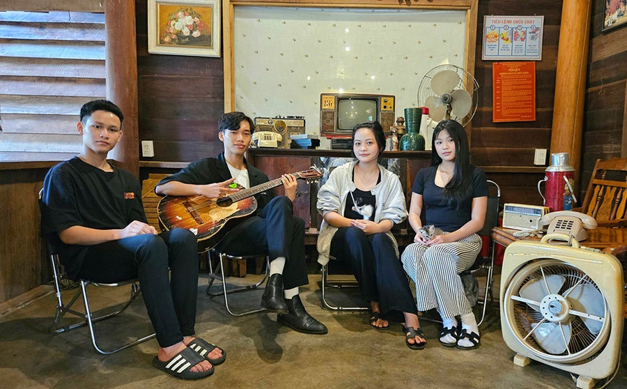 Bạn Trần Ngọc Long (người cầm đàn) cùng nhóm bạn quây quần đàn hát giữa không gian mang đậm dấu ấn thời gian. Ảnh: Ngọc Duy 1a.jpg