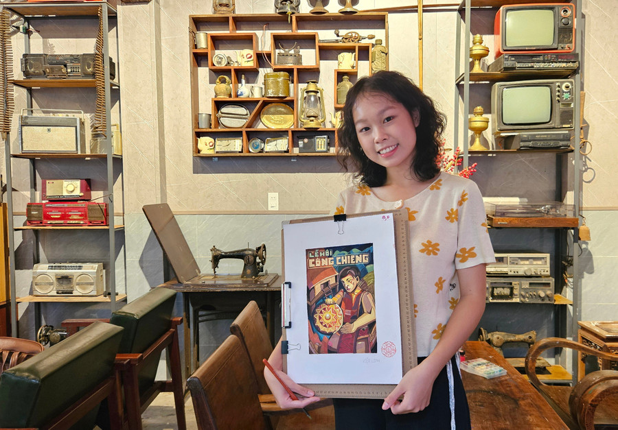Bạn Nguyễn Việt Linh (tổ 3, phường An Phú) giới thiệu bức vẽ về "Lễ hội Cồng chiêng" giữa không gian bài trí đậm màu hoài niệm. Ảnh: Ngọc Duy 4t.jpg