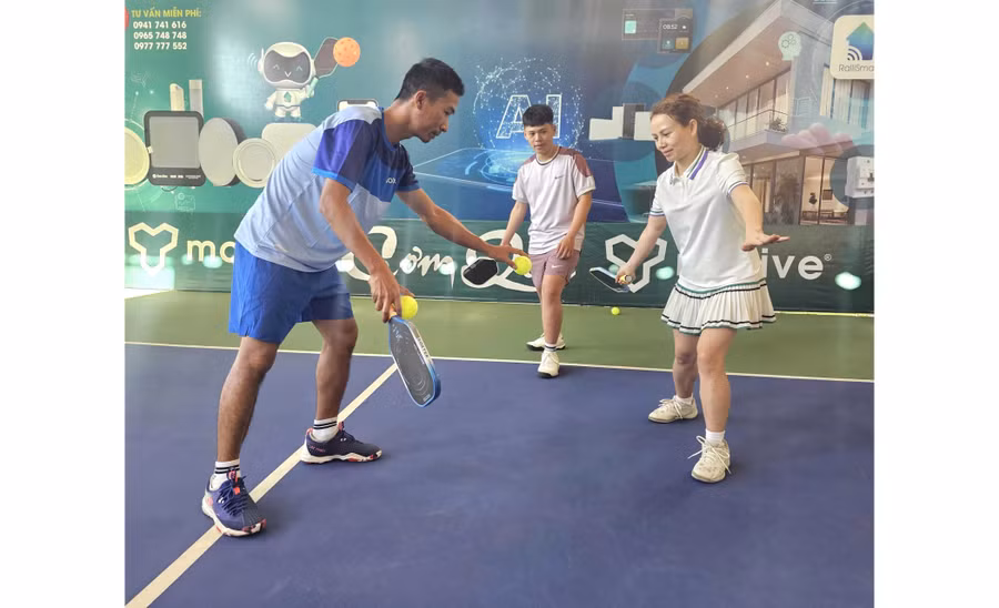 Huấn luyện viên Nguyễn Văn Hùng (bên trái) hướng dẫn học viên tập luyện pickleball. Ảnh: R’Ô HOK