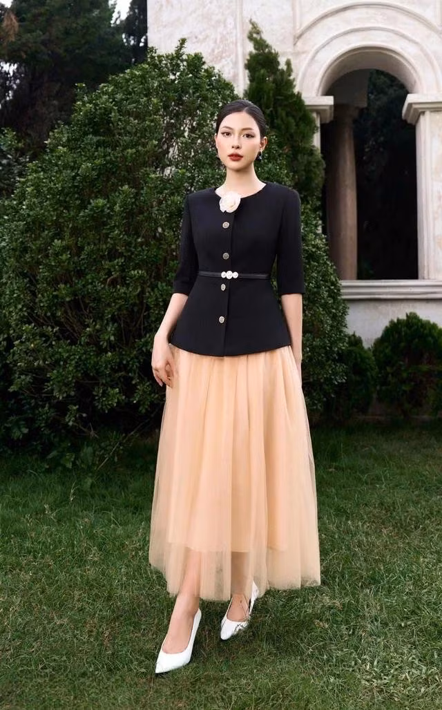 Áo vest cổ tròn với dáng peplum nhấn eo thon gọn cùng bông hoa cài trang trí tạo điểm nhấn. Chân váy xòe rủ nhiều lớp sở hữu hiệu ứng bồng bềnh dễ thương. Bộ đôi này không chỉ mang lại vẻ trang nhã cho quý cô mà còn giúp bạn tự tin tỏa sáng trong mọi dịp, từ đi làm đến đi chơi. ẢNH: MY WAY