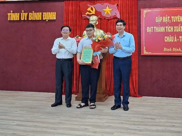 Bí thư Tỉnh ủy Bình Định Hồ Quốc Dũng (bên trái) và Phó Chủ tịch UBND tỉnh Bình Định Lâm Hải Giang (bên phải) trao thưởng cho em Lê Kiến Thành. ẢNH: OANH TRƯỞNG