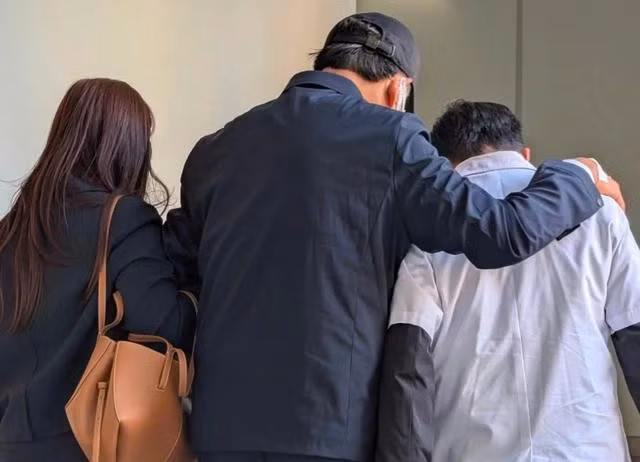 Ông Mai Tiến Dũng (giữa) được dìu vào phòng xử. ẢNH: P.V