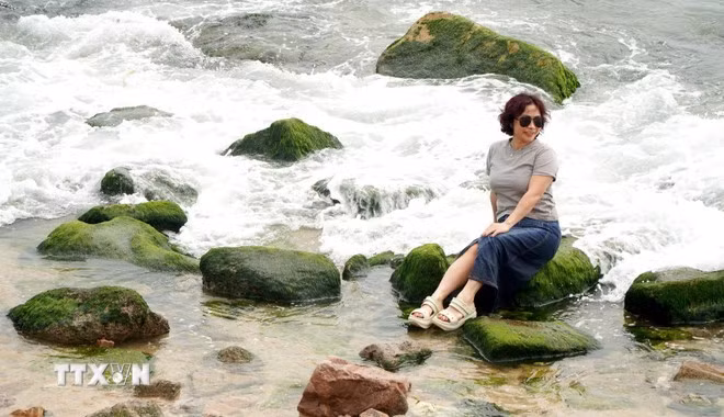 Du khách chụp ảnh tại bãi đá rêu Nhơn Hải. (Ảnh: Lê Phước Ngọc/TTXVN)