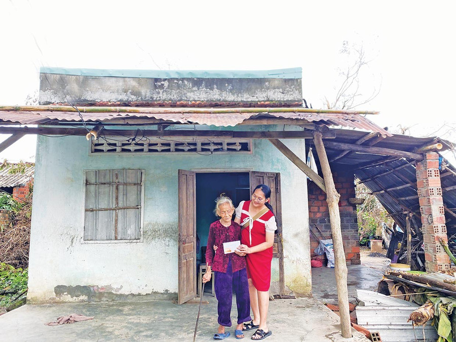 Chị Nguyễn Thị Lệ Hoàng (bìa phải) trao tiền hỗ trợ cho gia đình khó khăn để sửa chữa lại nhà ở sau bão lũ. Ảnh: NVCC