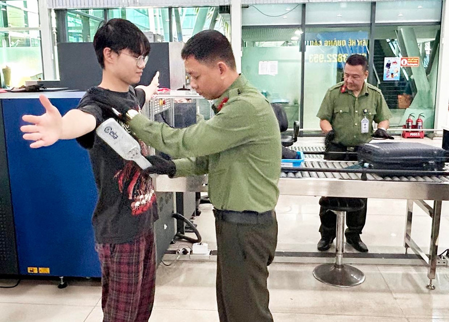 Lực lượng an ninh hàng không dò kim loại bằng thiết bị cần tay đối với hành khách khi qua cổng an ninh. Ảnh: K.A