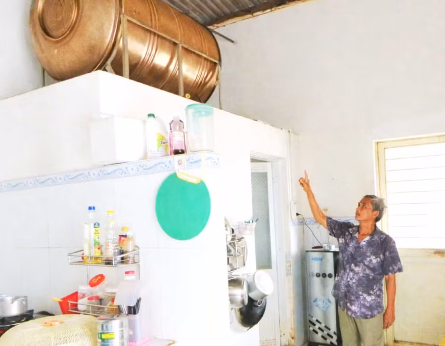 Nước giếng của gia đình ông Nguyễn Văn Sơn bị nhiễm phèn, bồn chứa nước lâu ngày có màu ố vàng, để có nước uống hằng ngày, gia đình ông phải mua máy lọc nước về sử dụng. Ảnh: V.L