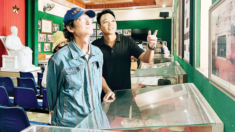 Anh Rmah Kawen (bên phải) giới thiệu cho khách tham quan về những tư liệu, hiện vật lịch sử tại Nhà lao Pleiku. Ảnh: Đồng Lai bg8-3.jpg