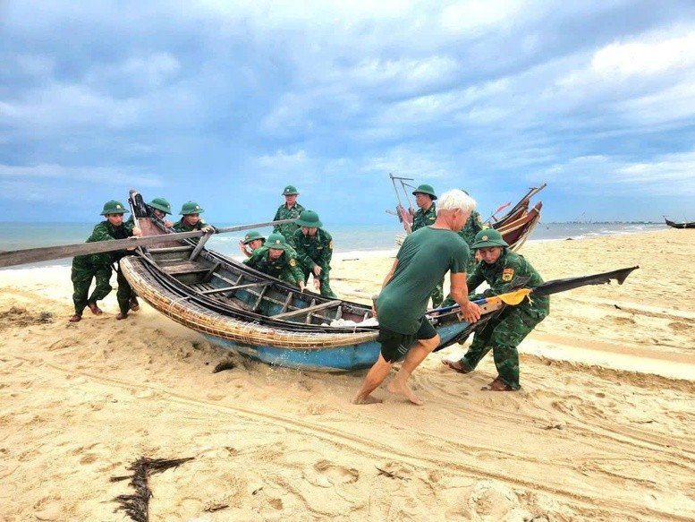 Bộ đội biên phòng Quảng Trị hỗ trợ người dân đưa tàu cá lên bờ tránh bão số 5. Ảnh nguồn VGP tranhbaoo.jpg