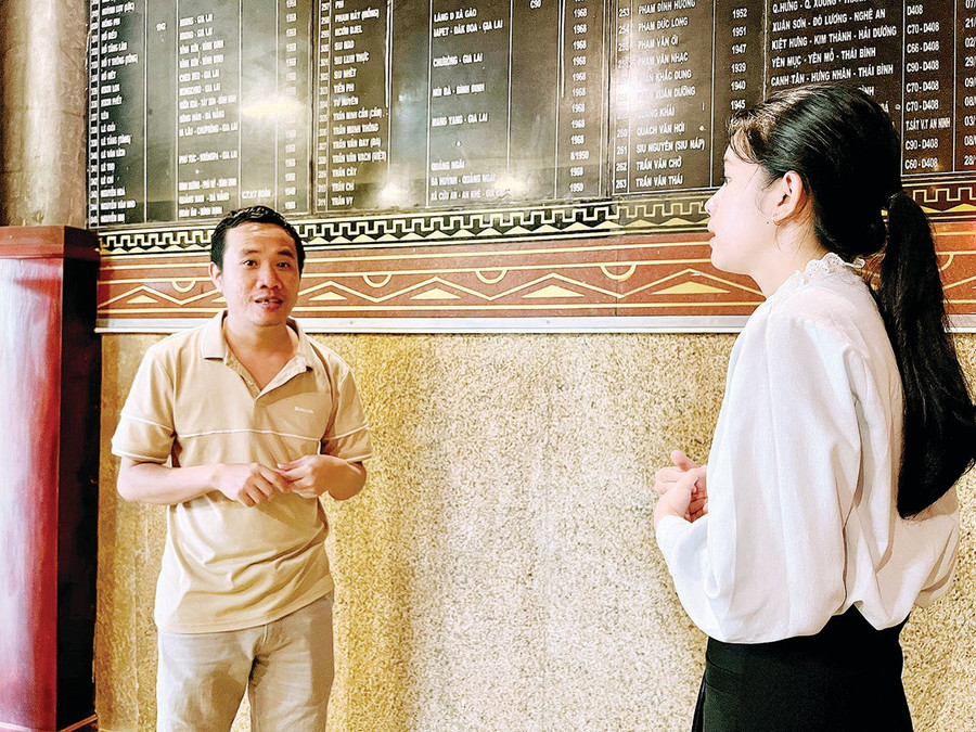 Anh Võ Phạm Xuân Nam đang thuyết minh về danh sách các liệt sĩ được khắc ghi tại Đền tưởng niệm liệt sĩ Hội Phú. Ảnh: Đồng Lai bg8-2.jpg