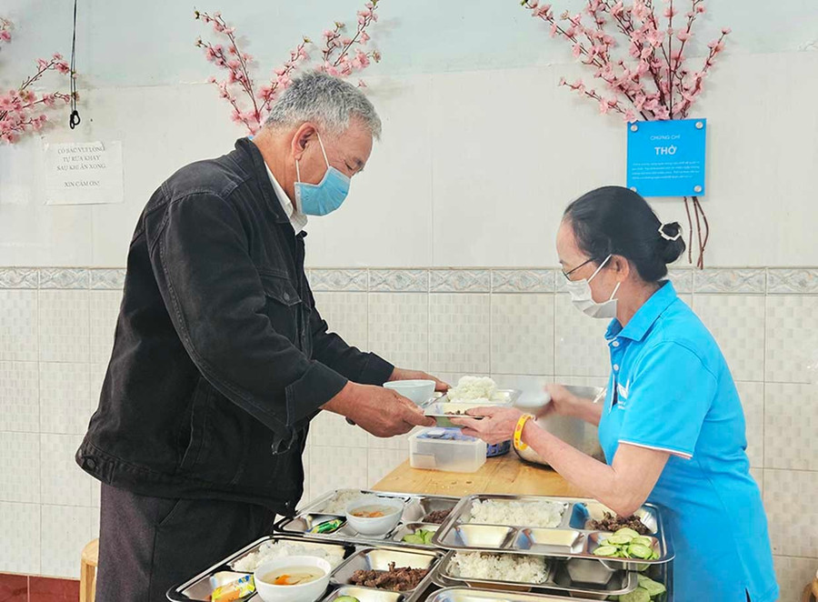 Tình nguyện viên quán cơm Yên Vui (bên phải) trao suất ăn đến người dân. Ảnh: Ngọc Duy 1chot.jpg