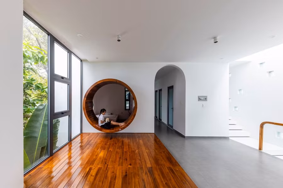 Ánh sáng tự nhiên tràn ngập căn phòng, kết hợp với tông màu trung tính như trắng, nâu, xám tạo nên không gian thanh bình và ấm áp. Nội thất được sắp xếp đơn giản nhưng thanh lịch, với một chiếc ghế đơn gần cửa sổ, tạo nên không gian lý tưởng để thư giãn hoặc đọc sách.