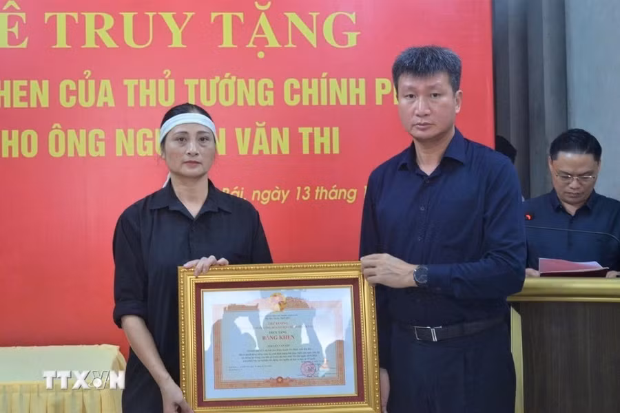 Chủ tịch UBND tỉnh Yên Bái Trần Huy Tuấn trao Bằng khen của Thủ tướng Chính phủ cho đại diện gia đình ông Nguyễn Văn Thi. (Ảnh: TTXVN phát)