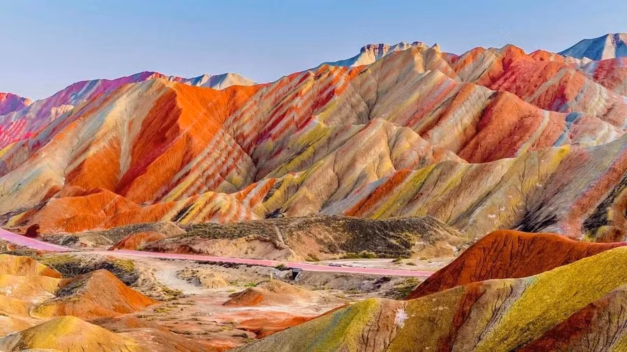 Nằm trong Công viên địa chất quốc gia Trương Dịch, dãy núi Cầu Vồng là một trong nhiều điều bất ngờ tuyệt đẹp của Trung Quốc. Những sọc màu đỏ thẫm, vàng và xanh rêu tô điểm cho sườn đồi; một khối đất đầy màu sắc tuyệt đẹp được hình thành trong hàng triệu năm do các mảng kiến tạo và thời tiết dịch chuyển, khiến đá sa thạch đỏ và nhiều loại khoáng chất hòa trộn với nhau