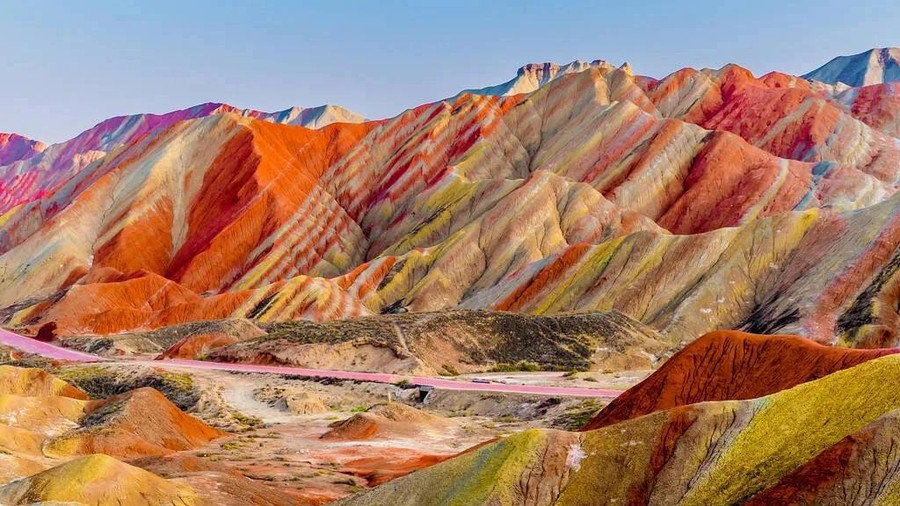 Nằm trong Công viên địa chất quốc gia Trương Dịch, dãy núi Cầu Vồng là một trong nhiều điều bất ngờ tuyệt đẹp của Trung Quốc. Những sọc màu đỏ thẫm, vàng và xanh rêu tô điểm cho sườn đồi; một khối đất đầy màu sắc tuyệt đẹp được hình thành trong hàng triệu năm do các mảng kiến tạo và thời tiết dịch chuyển, khiến đá sa thạch đỏ và nhiều loại khoáng chất hòa trộn với nhau