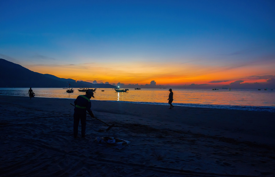 Ngoài những nhộn nhịp, ở một góc nhỏ trên bãi biển, hình ảnh chị lao công âm thầm, cặm cụi thu gom rác sớm trở thành điểm nhấn lặng lẽ mà ý nghĩa... ẢNH: NGUYỄN TRÌNH