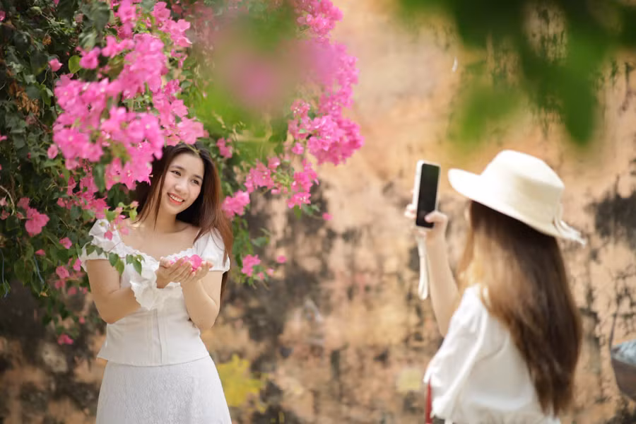 Bạn Nguyễn Nữ Bảo Châu (bên trái) cùng với nhóm bạn của mình từ TPHCM tìm tới con đường hoa giấy ở phường Vĩnh Trường sau khi xem trên mạng xã hội.