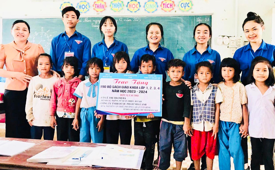 Cô Loan cùng học sinh Trường THPT Trần Quốc Tuấn trao sách giáo khoa cho học sinh khó khăn. Ảnh: M.K 1t.jpg