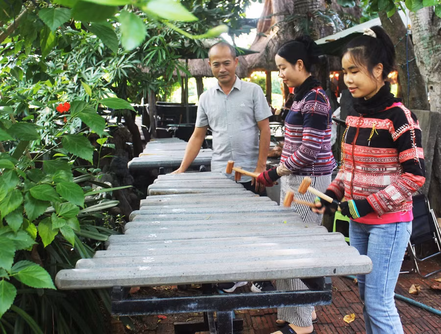 Nghệ nhân Nguyễn Minh Nghiệp hướng dẫn các bạn trẻ chơi đàn đá. Ảnh: Huyền Oanh