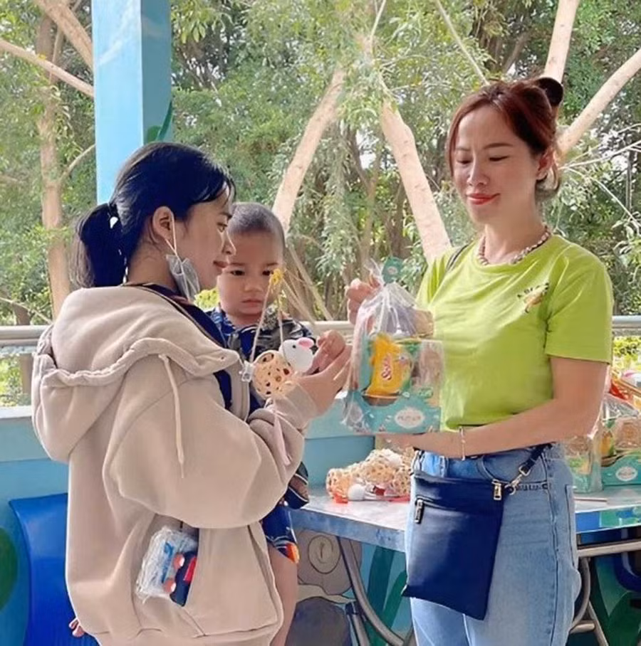 Chị Vòng Nhộc Kiều (bìa phải) trao những suất cháo nghĩa tình cho các em nhỏ.