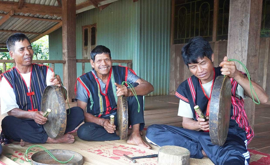 Ông Rơ Châm Kok (bìa phải) và người lớn tuổi trong làng cùng nhau chỉnh chiêng.