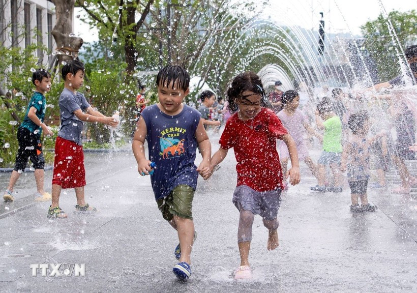 Các em nhỏ chơi đùa bên đài phun nước để tránh nóng tại Seoul, Hàn Quốc. (Ảnh: THX/TTXVN) nang-nong-cuc-doan.jpg