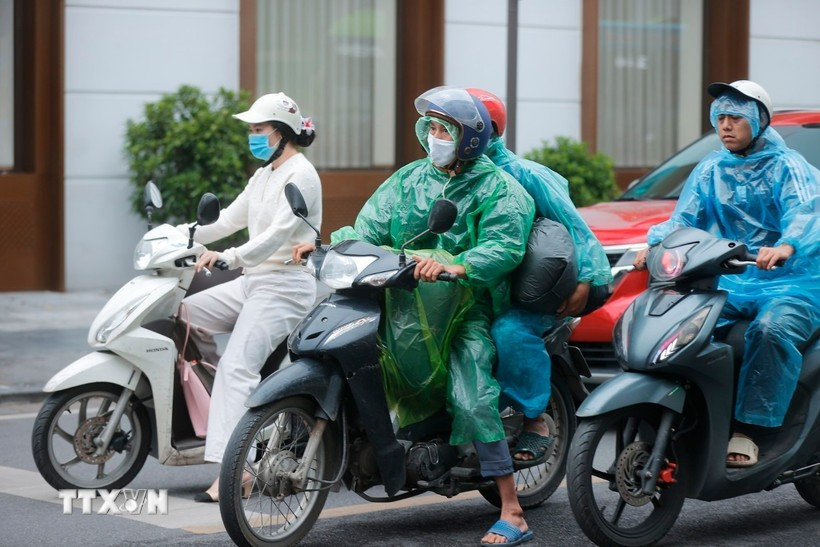 Nhiều người phải mặc áo mưa giữ ấm. (Ảnh: Minh Quyết/TTXVN)