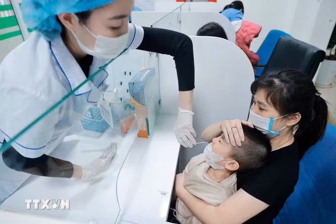 Nhân viên y tế lấy mẫu test cúm cho bệnh nhi. (Ảnh: Minh Quyết/TTXVN)