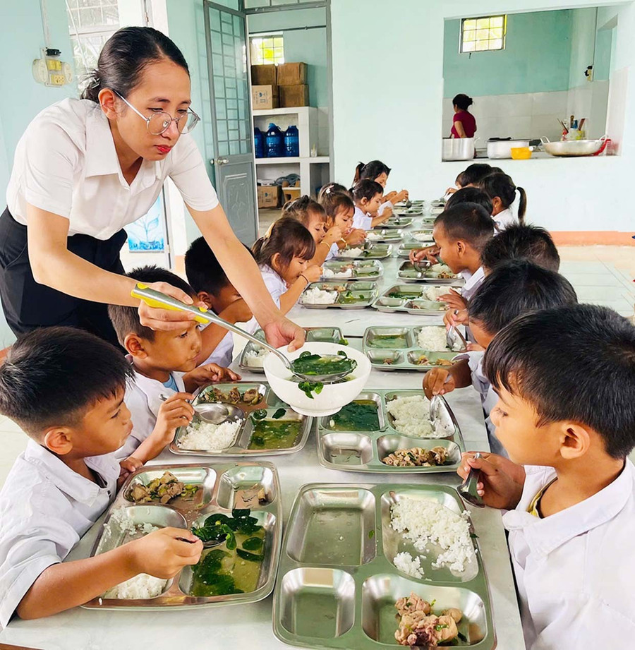 Cô giáo Nguyễn Thị Phú (Trường Tiểu học và THCS Đinh Núp, xã Pờ Tó) lấy thêm thức ăn cho học sinh. Ảnh: Vũ Chi