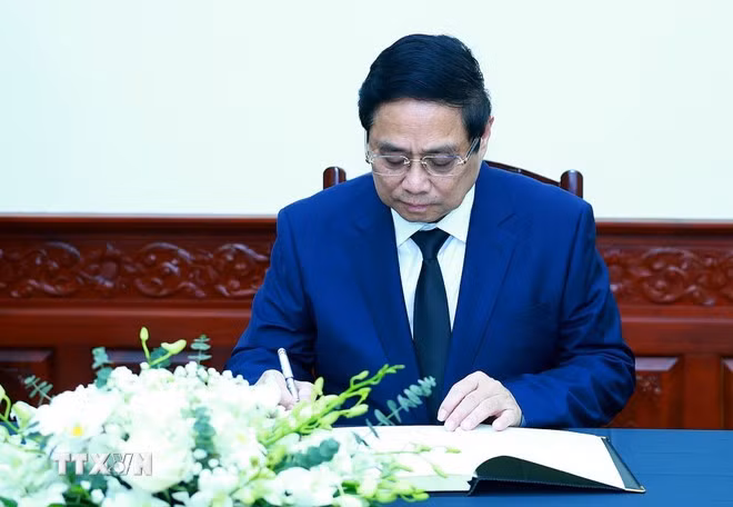 Thủ tướng Phạm Minh Chính ghi sổ tang chia buồn. (Ảnh: Dương Giang/TTXVN)