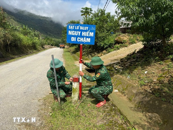 Chiến sỹ Đồn biên phòng Nhôn Mai cắm biển cảnh báo khu vực sạt lở. Ảnh: TTXVN phát Chiến sỹ Đồn biên phòng Nhôn Mai cắm biển cảnh báo khu vực sạt lở. Ảnh: TTXVN phát