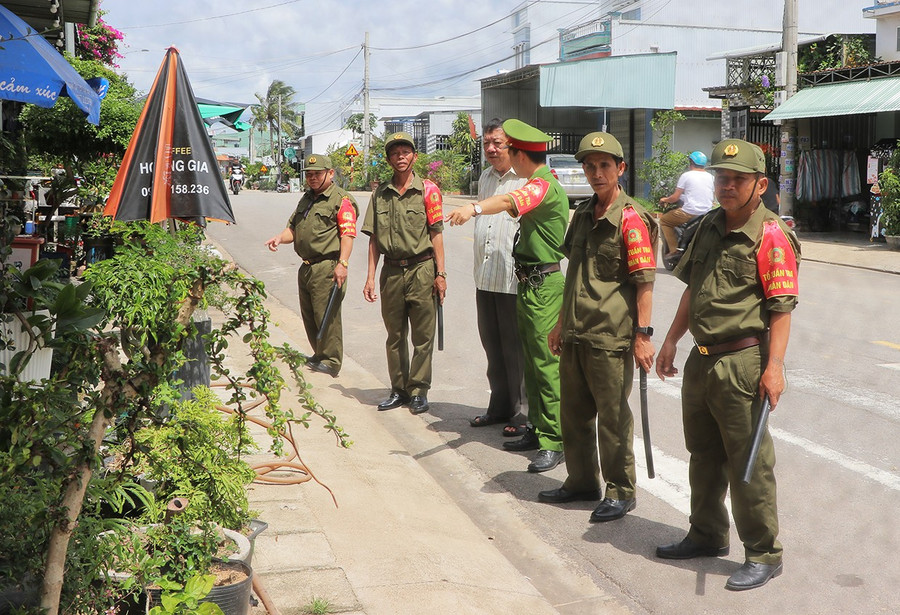 Các thành viên Tổ tuần tra nhân dân tổ dân phố 7 (phường Tây Sơn) nhắc nhở người dân bày cây cảnh đúng nơi quy định. Ảnh: N.M 2bg.jpg